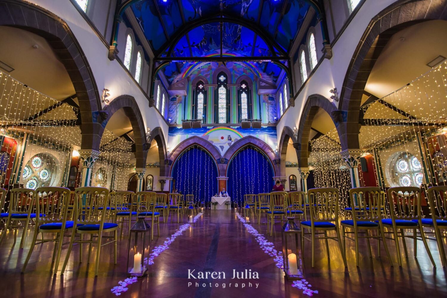 wide-angle interior of Òran Mór showing flower petals and candles lining the aisle