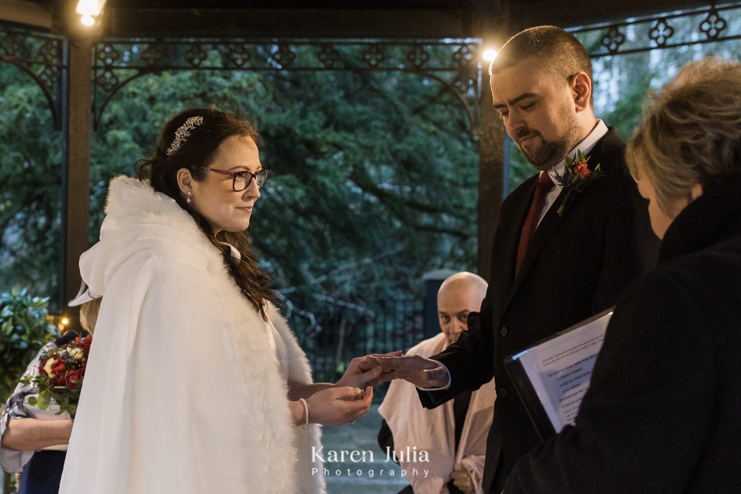 bride and groom exchange rings surrounded by fairy lights in the grounds of Crossbasket Castle