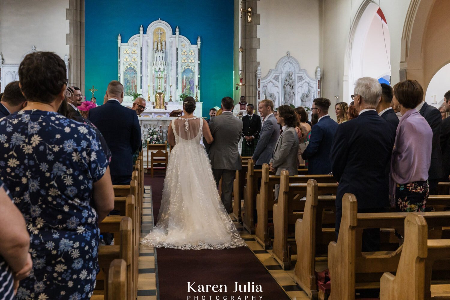 rear view of bride walking down the aisle with her dad to meet her groom