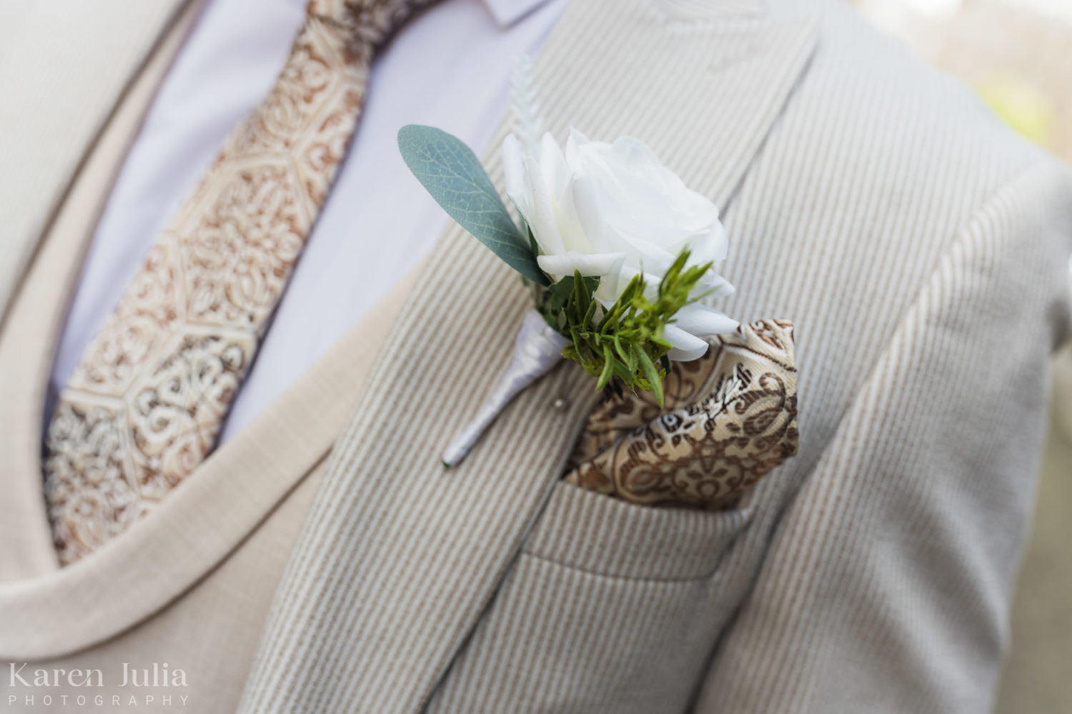 close up detail photo of grooms ivory suit and ivory button hole flower