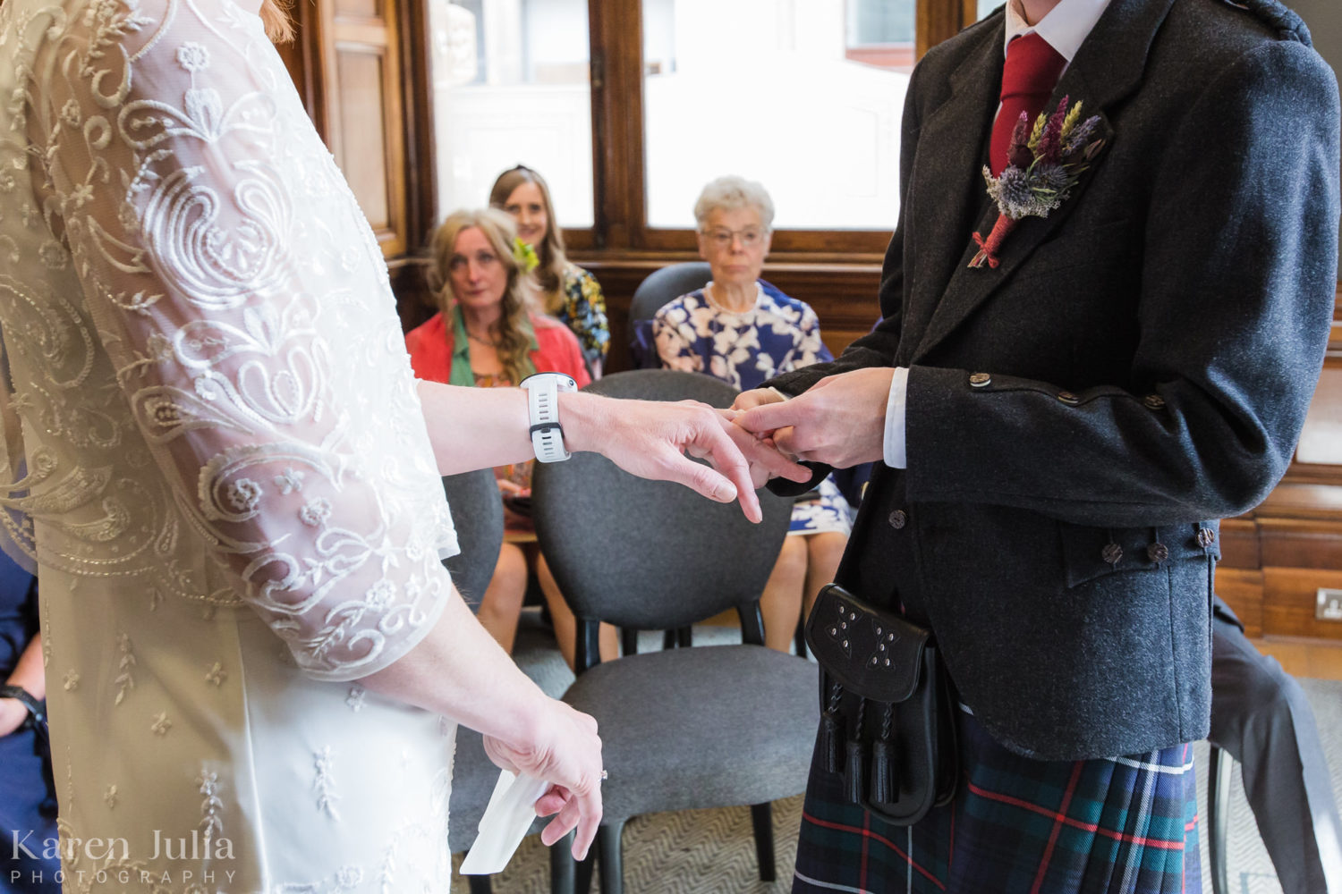 closeup photo of bride and groom exchanging rings in the Clyde Room
