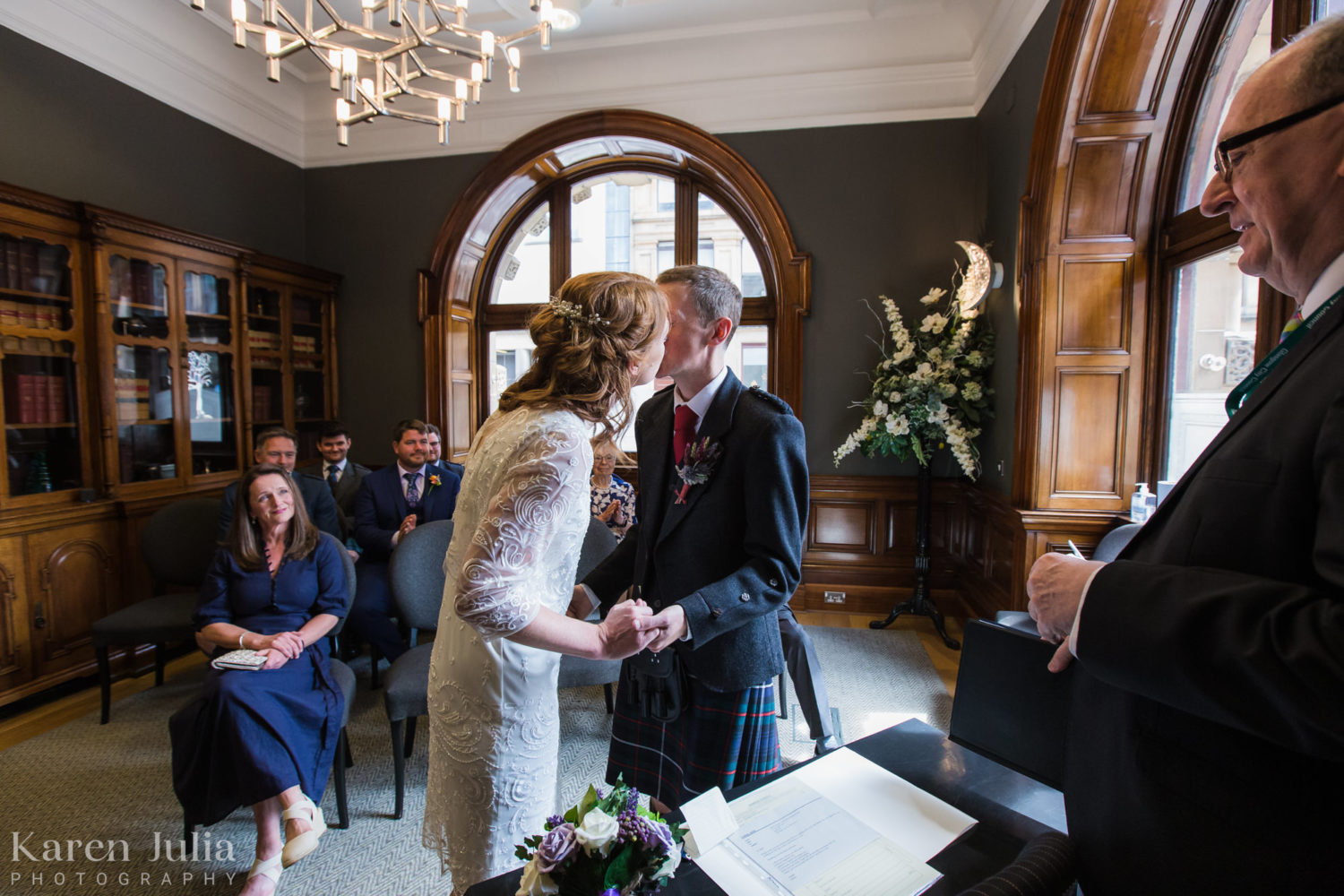 bride and groom kiss at the end of their wedding ceremony as their guests celebrate