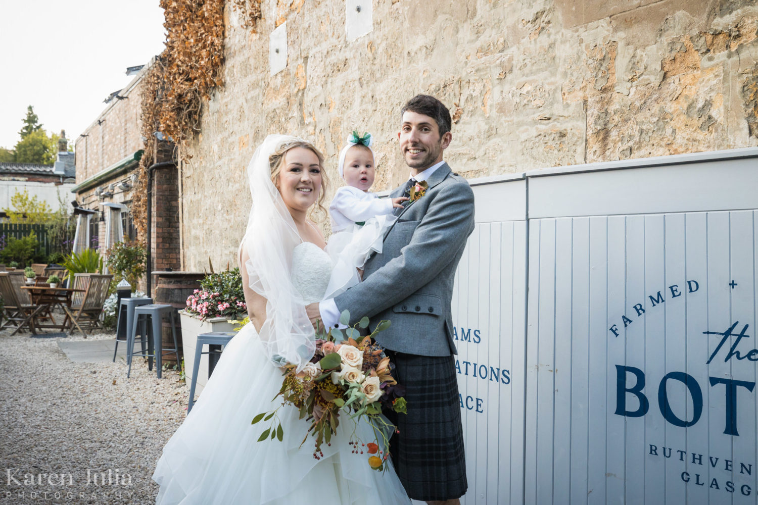 bride and groom portrait with their baby at the entrance to the Bothy