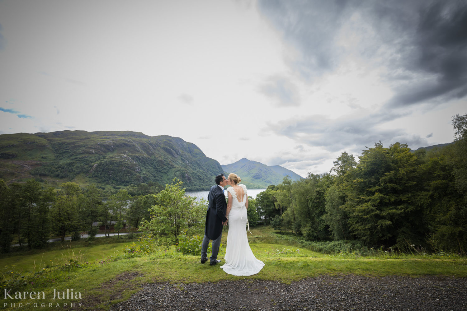 bride and groom share a kiss whilst looking over Loch Shiel