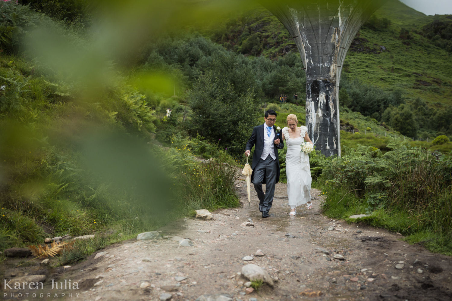 Candid photo of bride and groom walking down from the Glenfinnan Viaduct