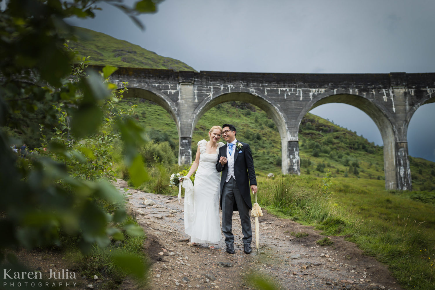 bride and groom briefly stop for a posed portrait photo with Glenfinnan Viaduct in the background