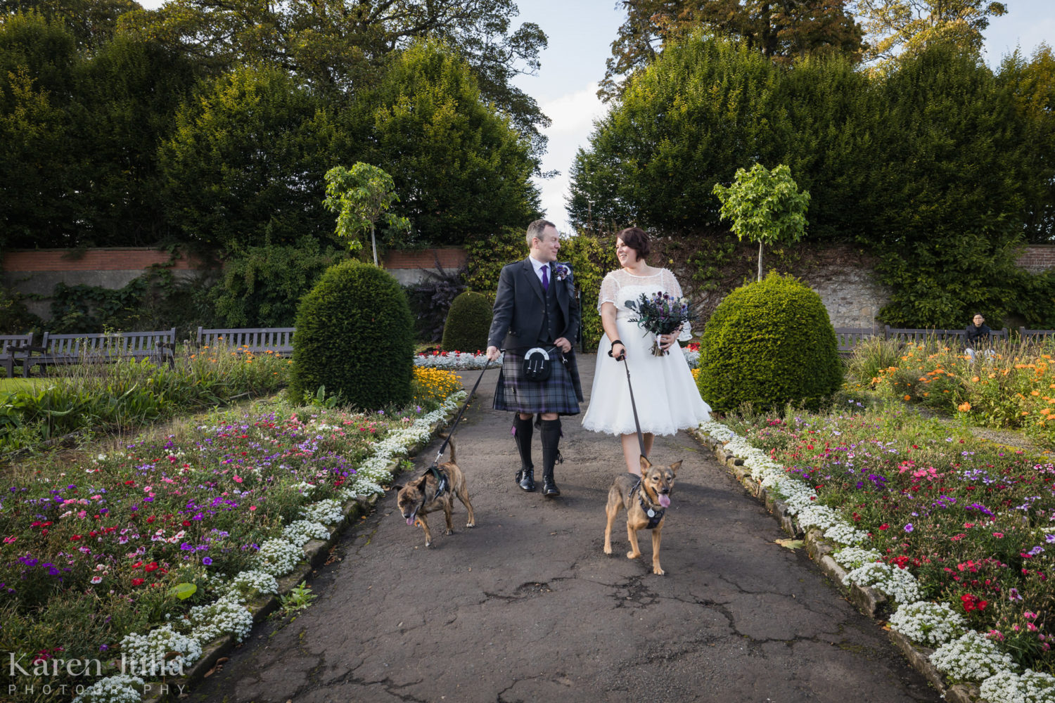 bride and groom walking in the Victorian walled garden with their dogs on their wedding day