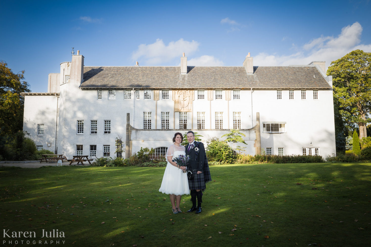 bride and groom portrait on their wedding day with house for an art lover in the background