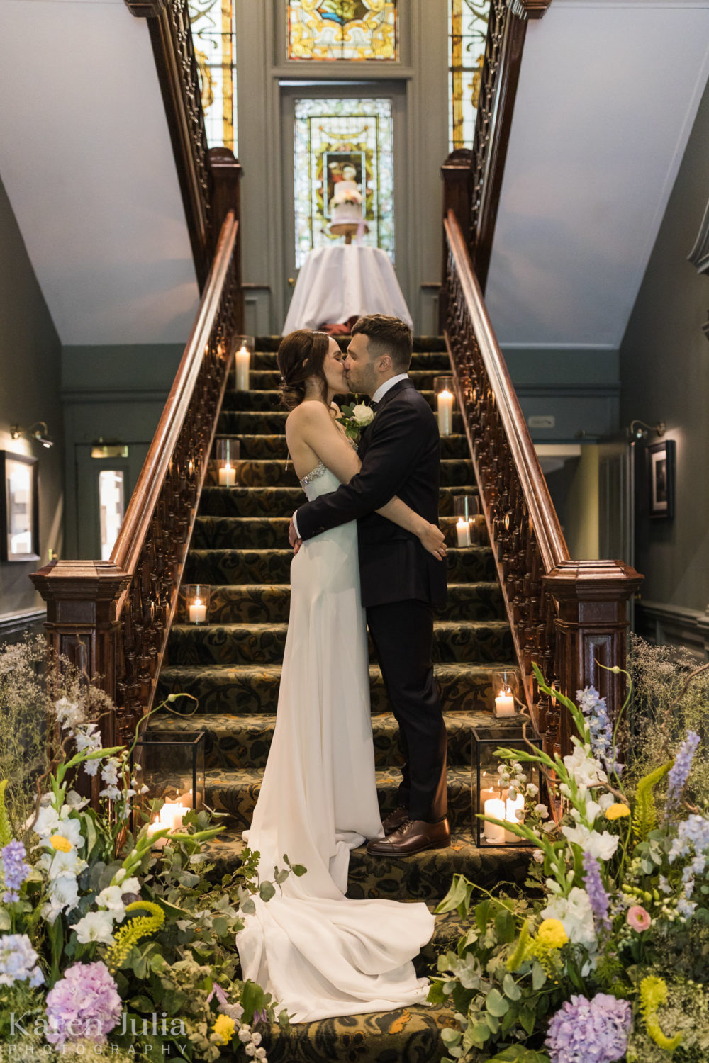 bride and groom embrace on the stairs at One Devonshire Gardens, surrounded by florals