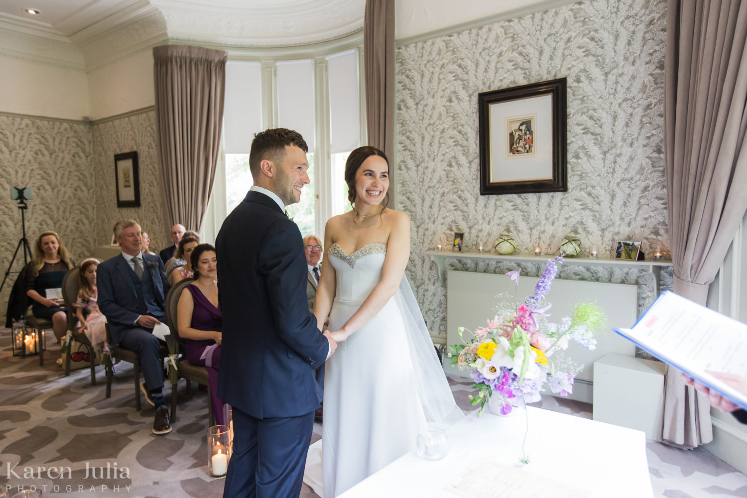 bride and groom holding hands during their wedding ceremony in the Glenlivet room at One Devonshire Gardens