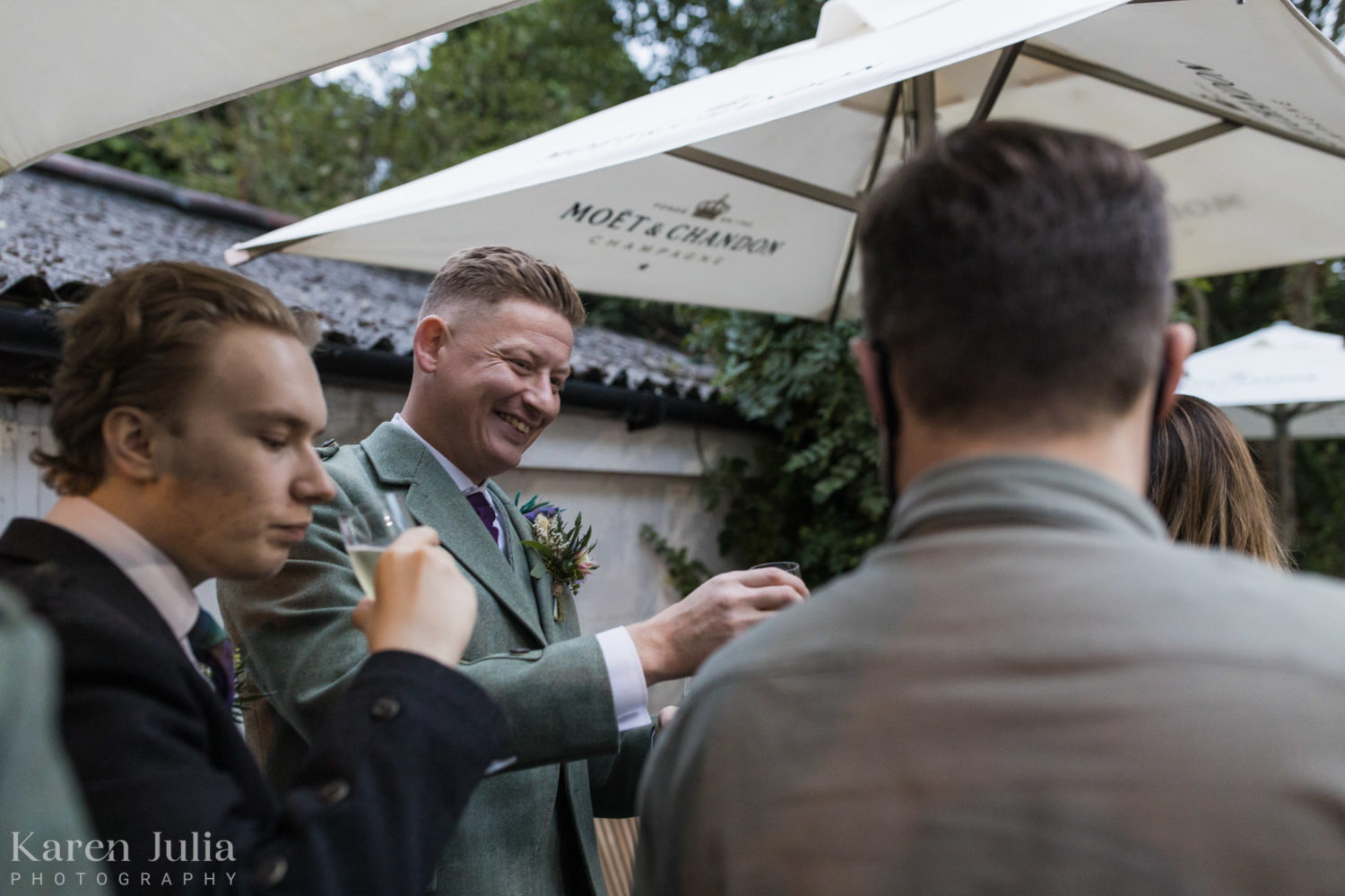 groom chatting with guests during wedding reception in the Bothy garden