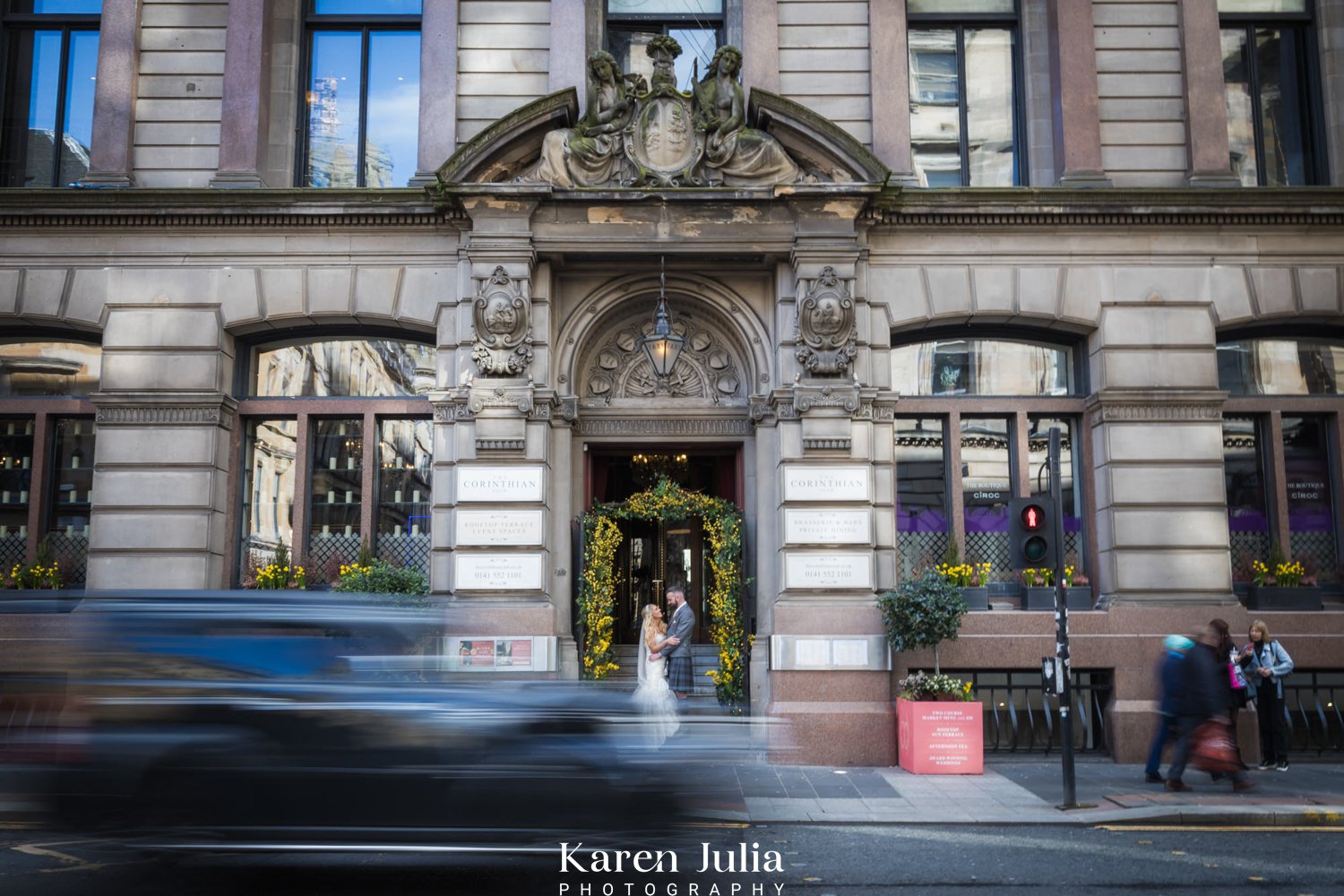 bride and groom portrait at the entrance of The Corinthian Club with moving traffic