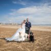 bride and groom pose for a couple portrait on Ardrossan south beach with their dogs