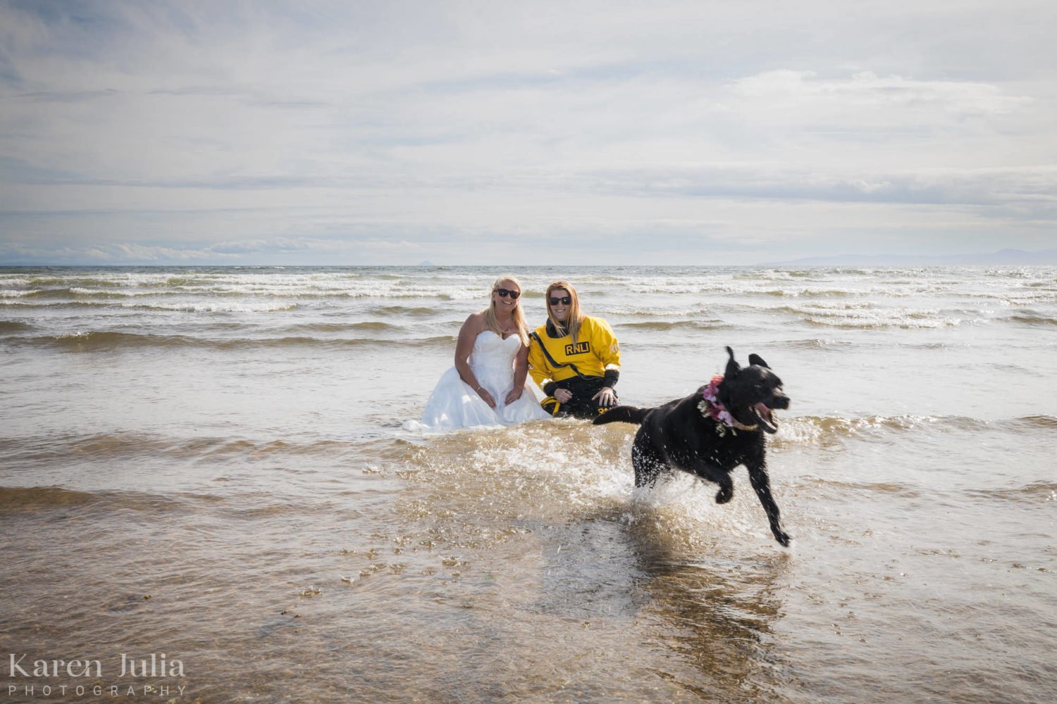 bride in the water with RNLI volunteer and her black labrador