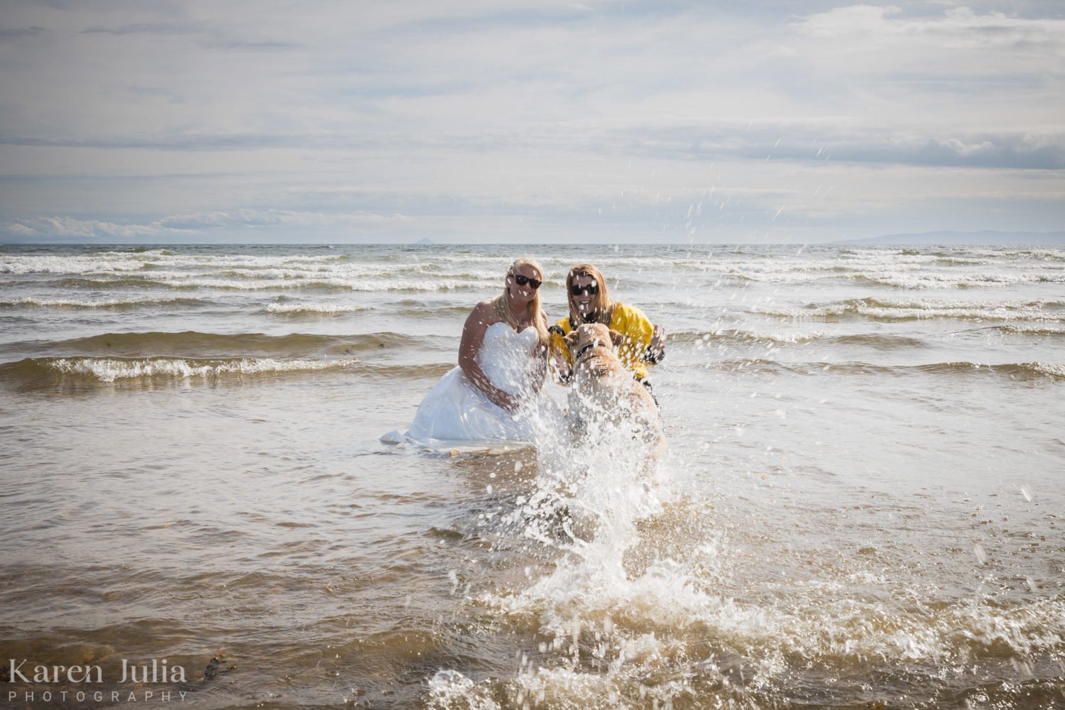 golden labrador runs towards bride as she has a portrait in the water at Ardrossan south beach