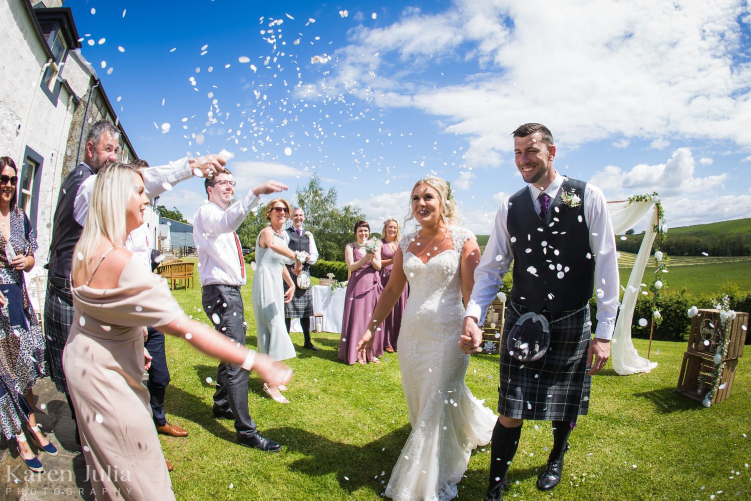 bride and groom smile whilst guests throw confetti