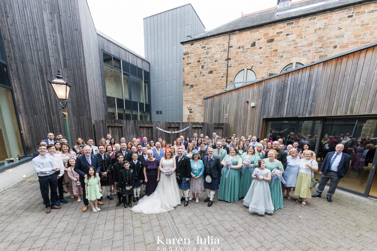 group photo of bride and groom and wedding guests in the courtyard at Maryhill Burgh Halls