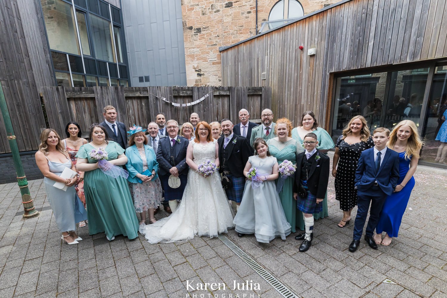 group photo of bride and groom and wedding guests in the courtyard at Maryhill Burgh Halls