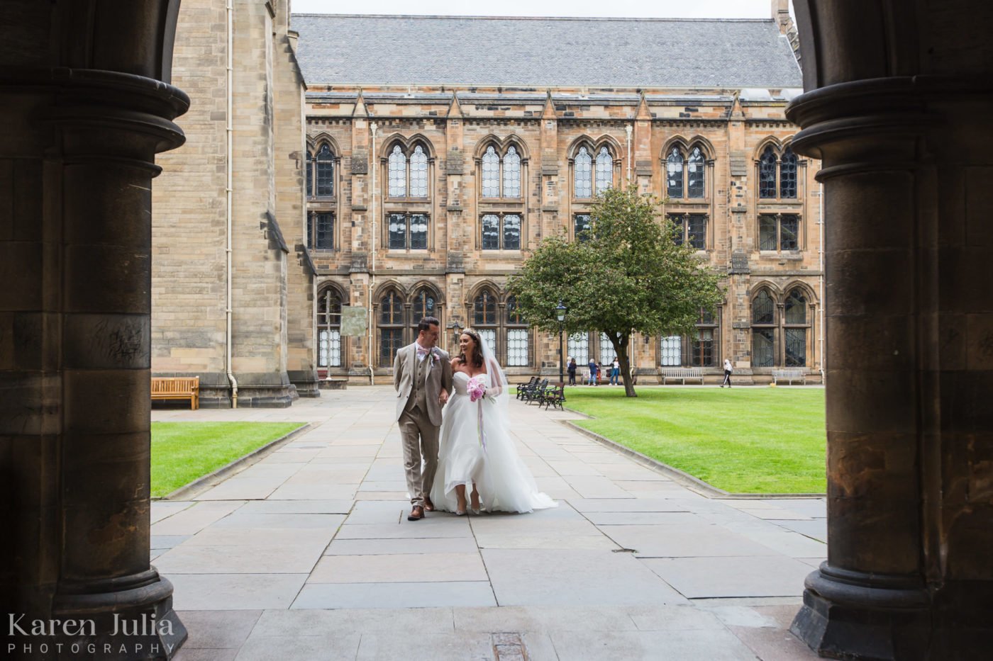 bride and groom walking together in the University of Glasgow courtyard on their wedding day
