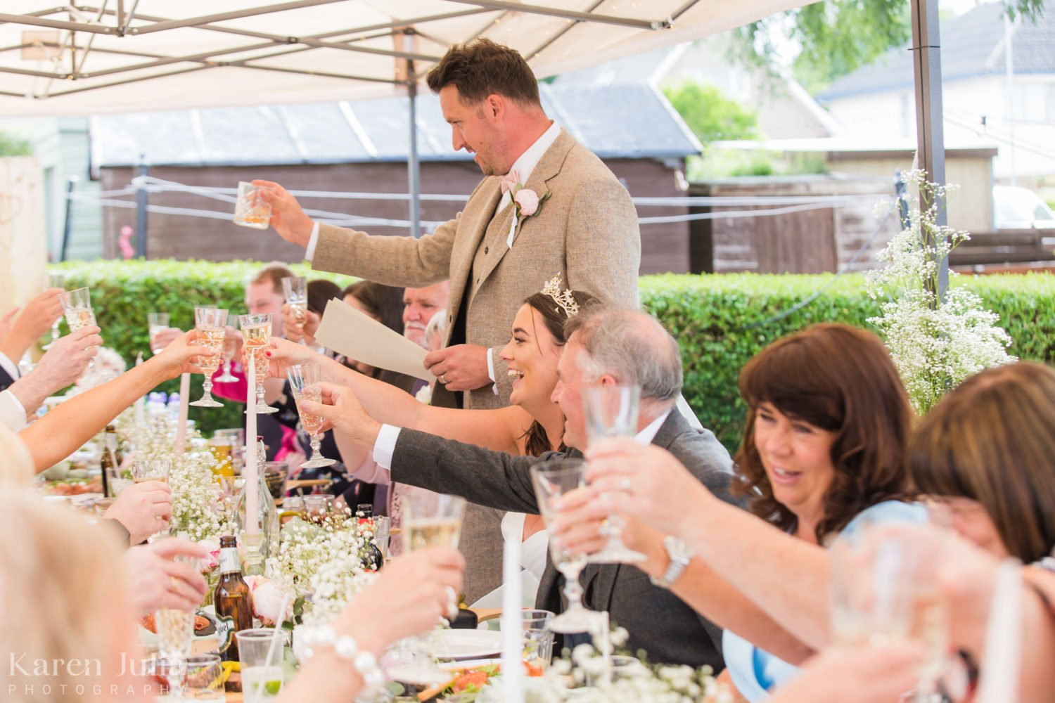 groom and guests raise glasses to toast during garden party reception